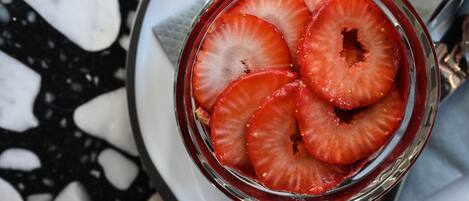 Un dessert aux fruits accompagné d’un verre de fraises coupées en tranches.