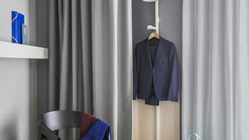 Een kamer met een stoel, een kapstok met een pak, een tas en een lamp.