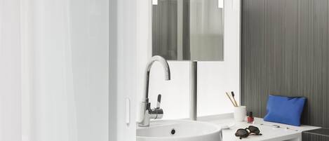 A modern bathroom with a white sink, a mirror, and a towel rack.