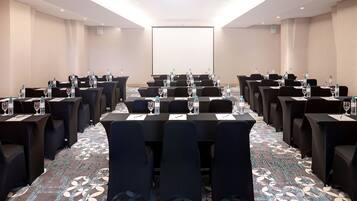 A conference room with multiple tables, chairs, and water bottles.