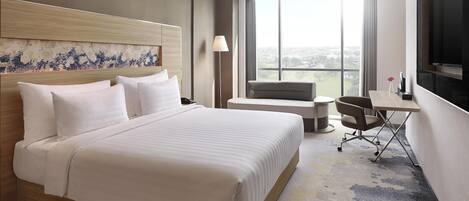 Una habitación de hotel moderna con una cama grande, un escritorio, una silla y un televisor.