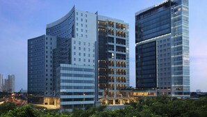 Un hotel modern amb façana corbada, diverses plantes i exterior de vidre.