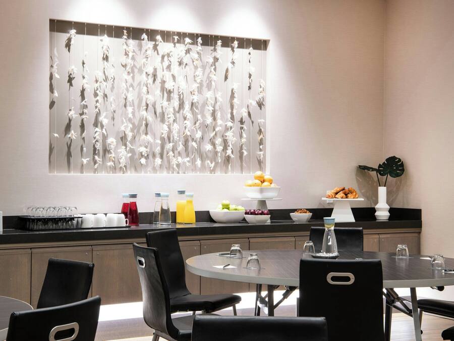 A modern dining area with a round table, black chairs, and a decorative wall piece.