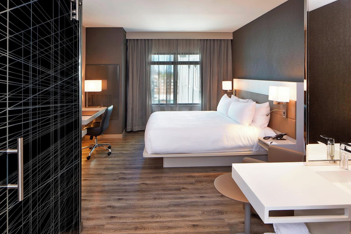 A hotel room with a large bed, bedside tables, a desk, and a chair.