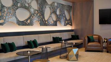 Un espace de détente moderne avec un canapé, des tables rondes et un fauteuil en cuir.