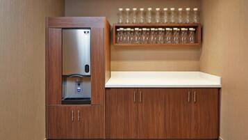 A kitchenette with a built-in refrigerator, a microwave, and a shelf with multiple glasses.