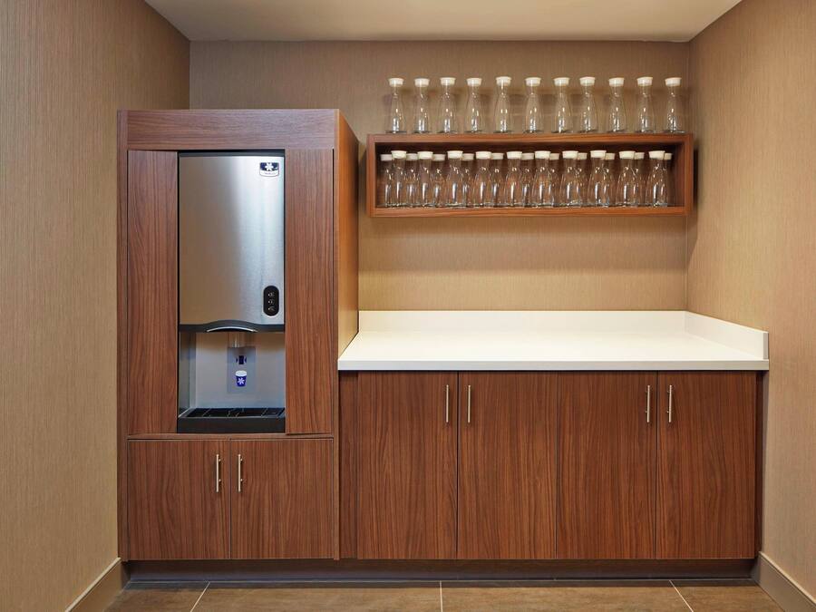 A kitchenette with a built-in refrigerator, a microwave, and a shelf with multiple glasses.