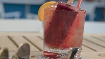 A glass of iced drink with a straw and a slice of fruit on a wooden table.