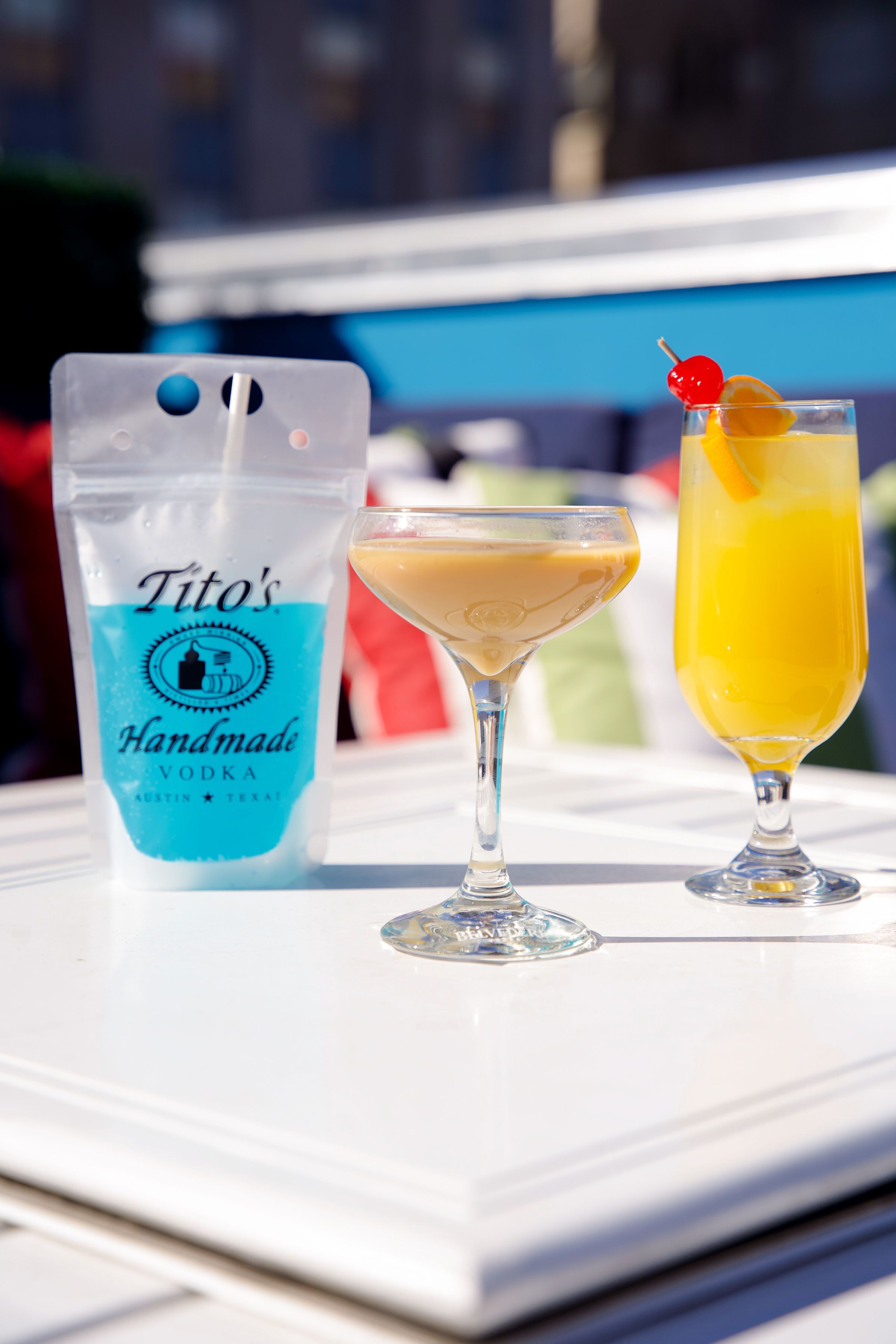 A table with a bottle of Tito's Handmade Vodka and two drinks, one in a martini glass and one in a highball glass.