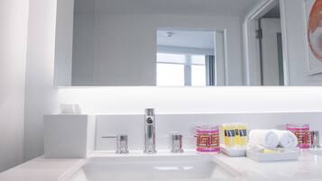 A modern bathroom with a white sink, a large mirror, and various toiletries on the counter.
