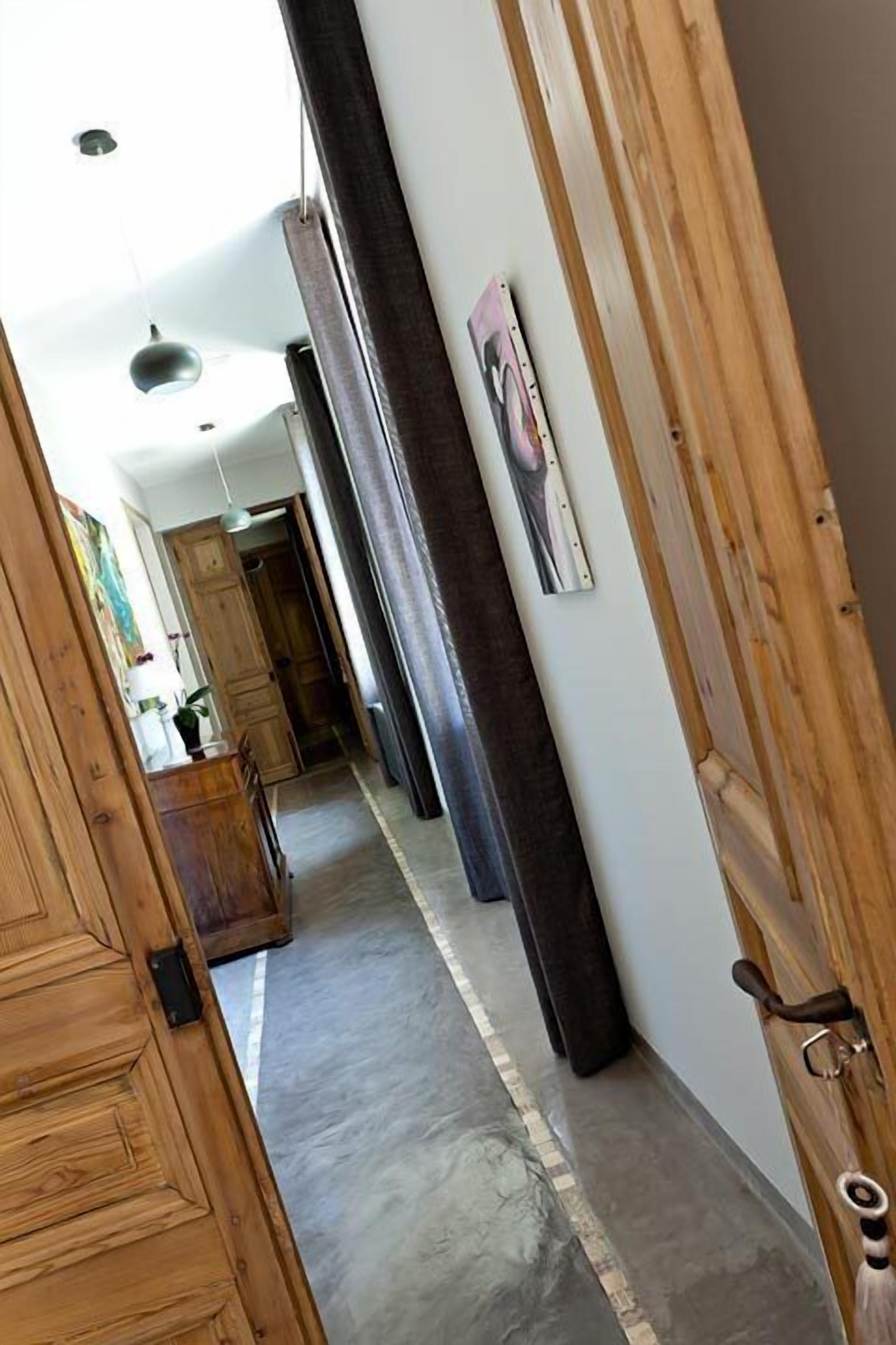 A hallway with wooden doors, a dark wall, and a light-colored floor.