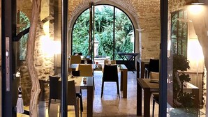 Un espacio interior con un arco de piedra que conduce a un comedor con mesas y sillas.