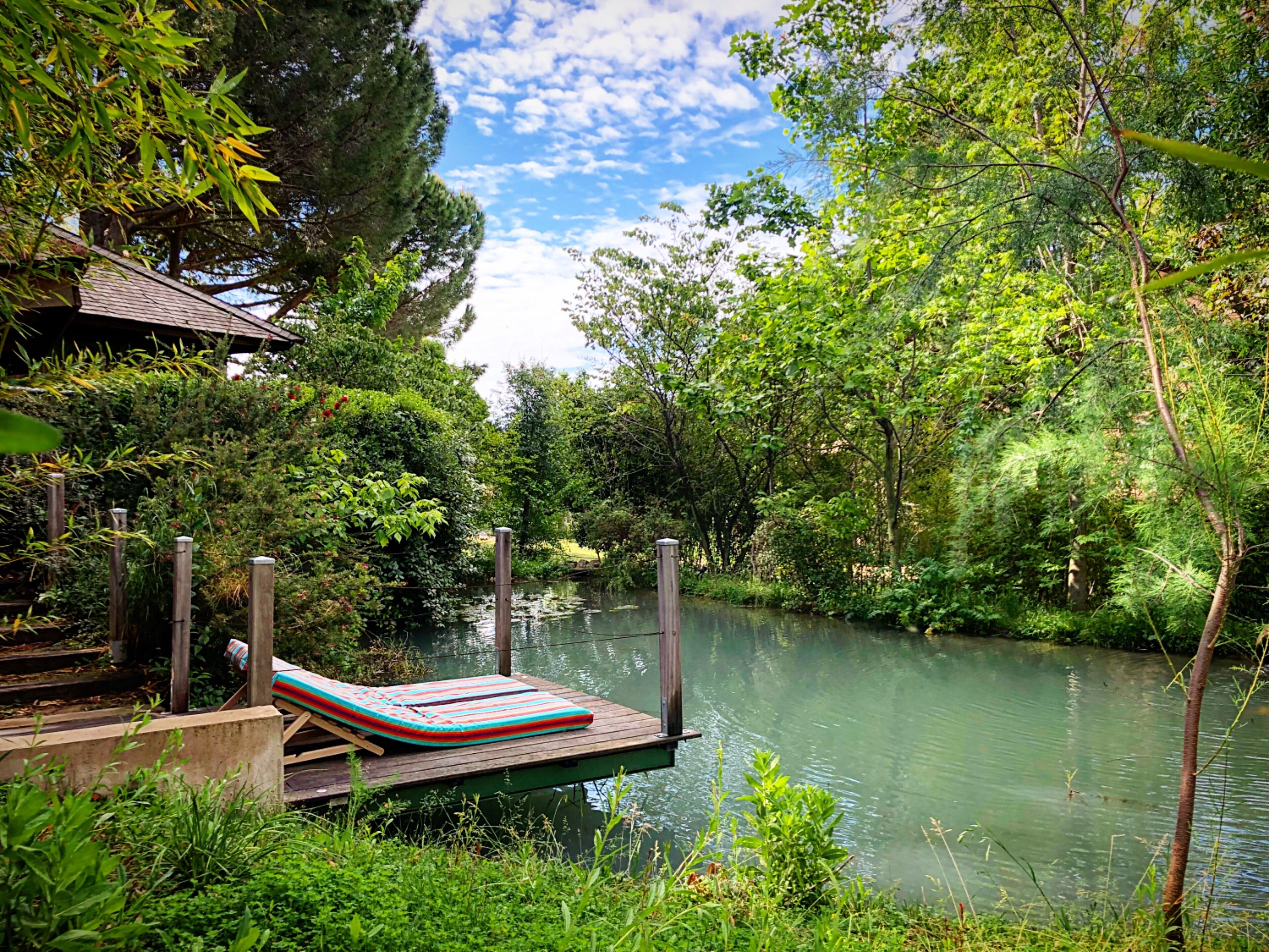 Une terrasse au bord de la rivière, avec un fauteuil de relaxation et une petite structure en bois.