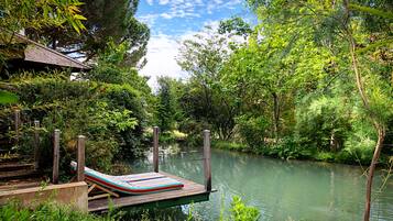 Une terrasse au bord de la rivière, avec un fauteuil de relaxation et une petite structure en bois.