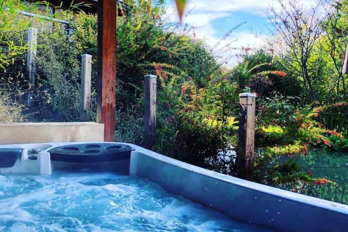 Ein Whirlpool in einem Garten mit einer hölzernen Überdachung.