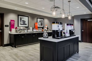 Uma cozinha moderna com um espaço para café, incluindo várias máquinas de café e uma variedade de xícaras.
