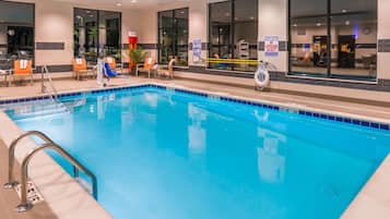 A hotel pool area with clear blue water, a lifeguard chair, and a sign indicating no lifeguard on duty.