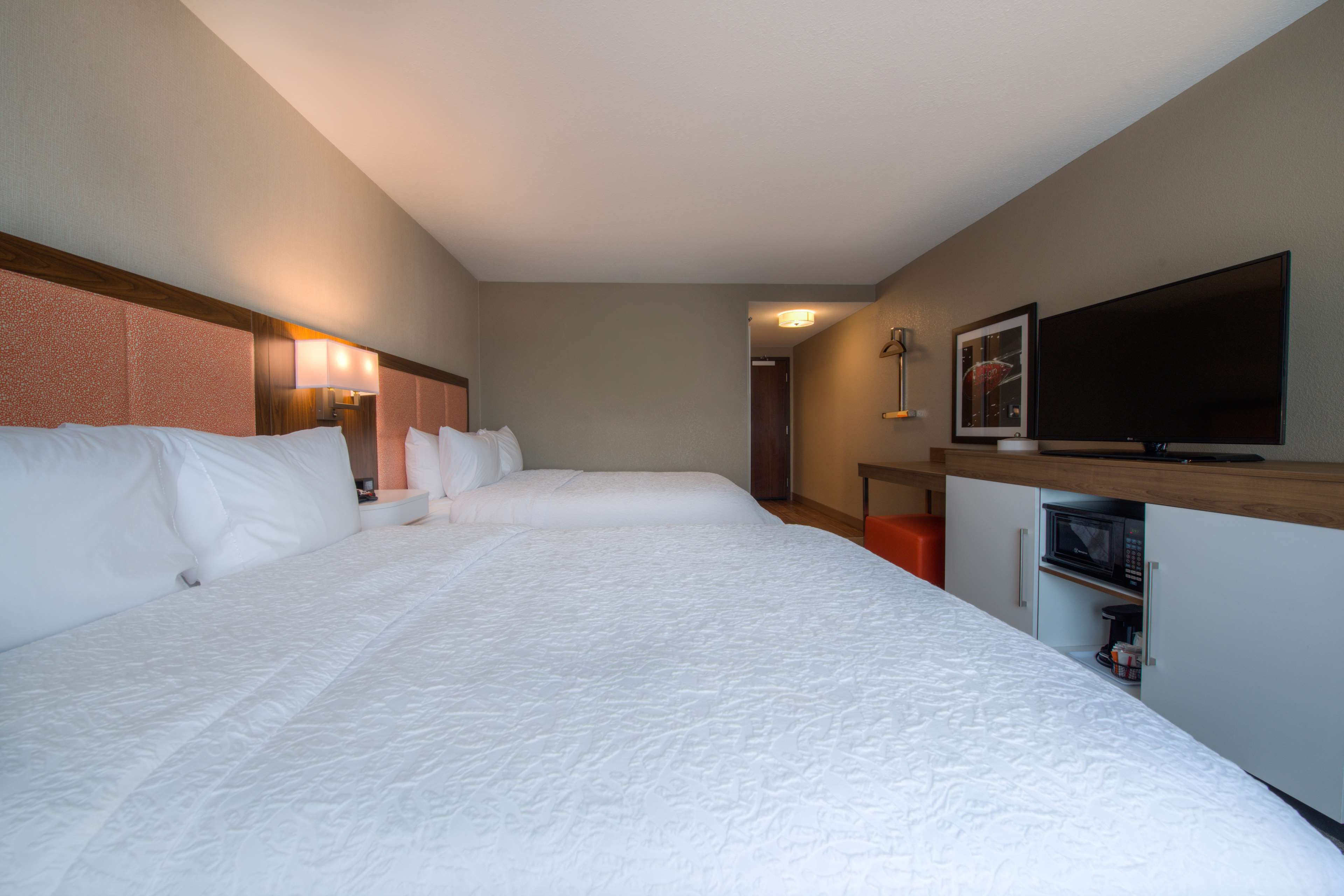Een hotelkamer met een groot bed, een flatscreen televisie, een magnetron en een klein kastje.