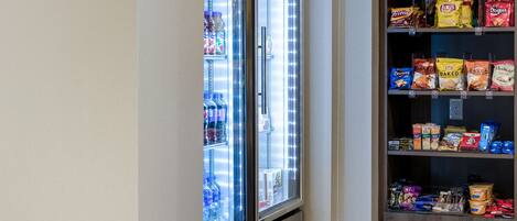 Máquina expendedora llena de aperitivos y un refrigerador con un rótulo que dice 'mercado'.