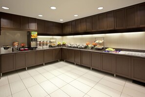 A modern kitchen with dark wooden cabinets, a stainless steel refrigerator, and a variety of food items displayed on the counter. - Residence Inn by Marriott Dallas Plano/Richardson at Coit Rd (Plano)