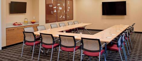 A conference room with a long table, chairs, a TV, and a wall with a map.