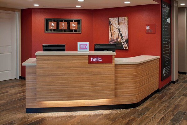 A reception desk with a 'hello.' sign, two monitors, and a framed 'Stay, Work, Play' sign on the wall. - TownePlace Suites by Marriott Richmond (Richmond)