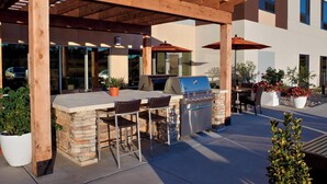 An outdoor patio with a grill, seating, and potted plants. - TownePlace Suites by Marriott Richmond (Richmond)