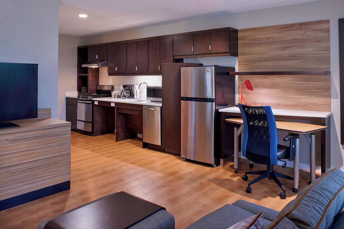 A modern kitchen with dark wood cabinets, stainless steel appliances, and a wooden accent wall.