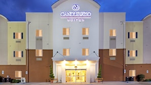 Um hotel com uma placa de destaque que diz 'CANDLEWOOD SUITES' e uma fachada simétrica com janelas uniformemente espaçadas.