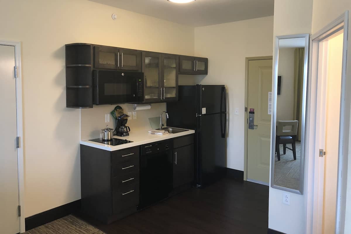 A compact kitchen with dark cabinets, a black refrigerator, a microwave, and a coffee maker.
