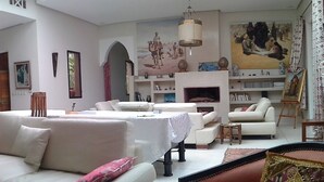 Un salón espacioso con un amplio sofá, un televisor y diversas obras de arte en las paredes.