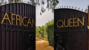 Una entrada con reja que muestra las palabras 'AFRICAN' y 'QUEEN' en letras doradas.