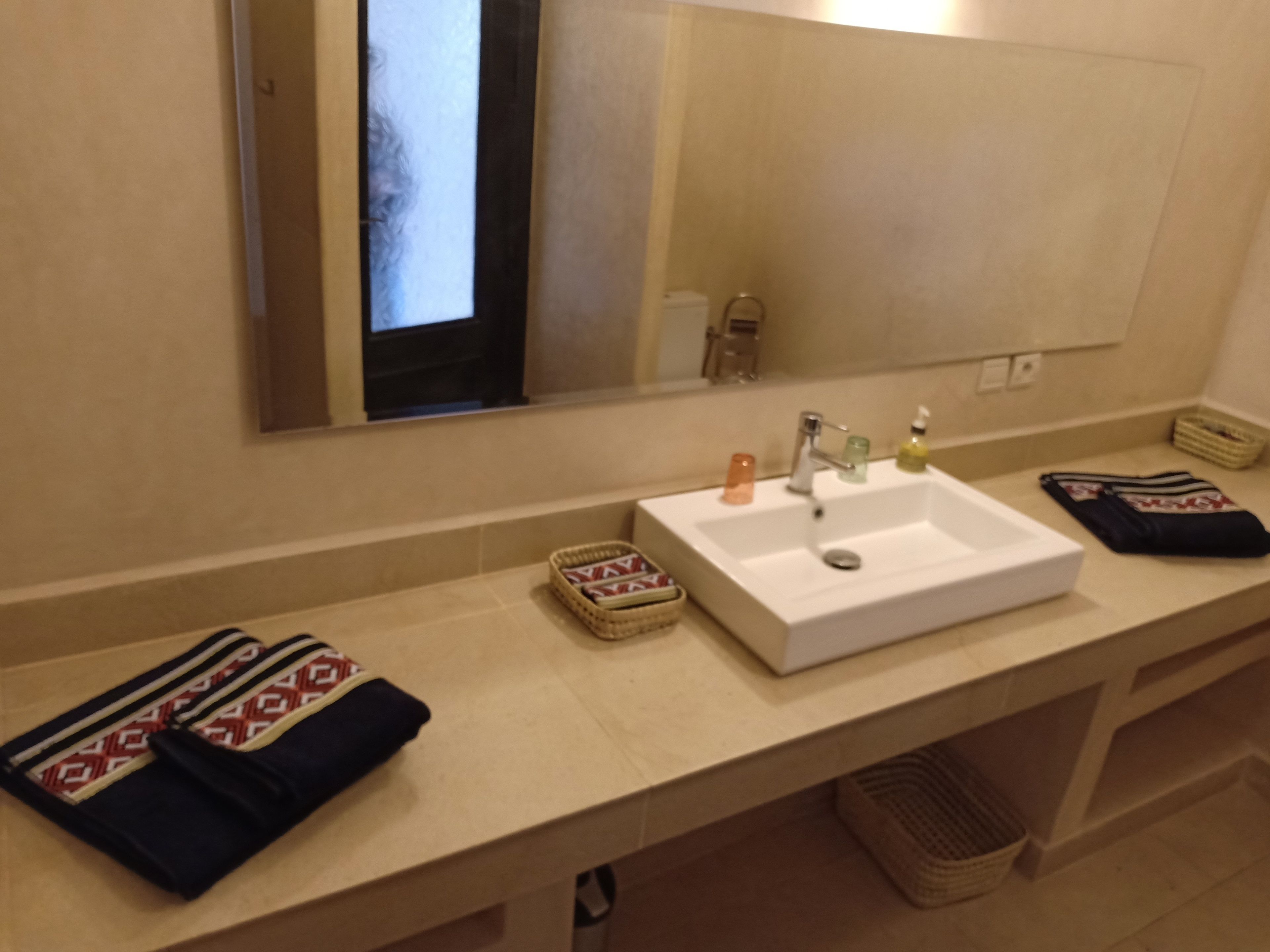 Un baño con un lavabo blanco, un espejo y un toallero.