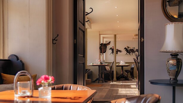 Una habitación con zona de comedor, sofá, mesa con un florero y lámpara.