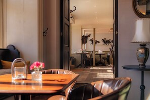 Una habitación con zona de comedor, sofá, mesa con un florero y lámpara.