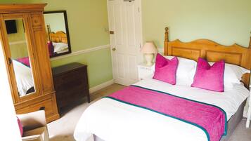 A bedroom with a bed, a nightstand, a dresser, a mirror, and a door.