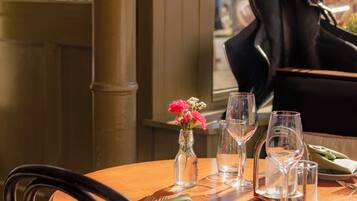 A dining table set with glasses, cutlery, and a vase of flowers.