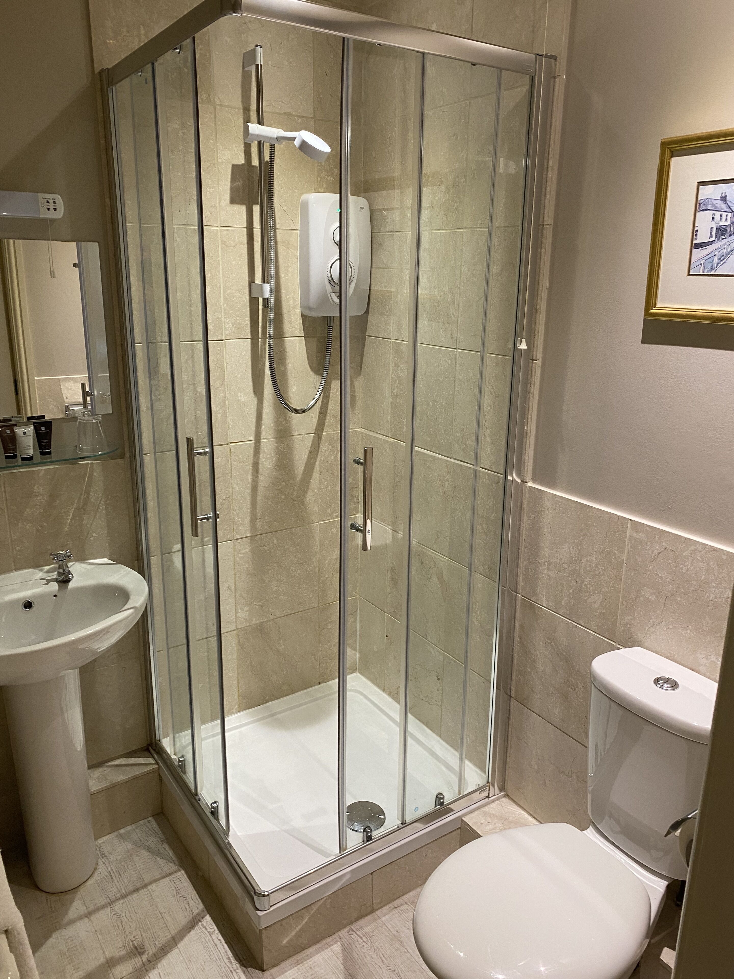 Une salle de bain moderne avec une douche à parois de verre, un lavabo sur colonne et des toilettes.
