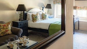 Un dormitorio con cama, mesitas de noche, un espejo y una mesa de centro con juego de té.