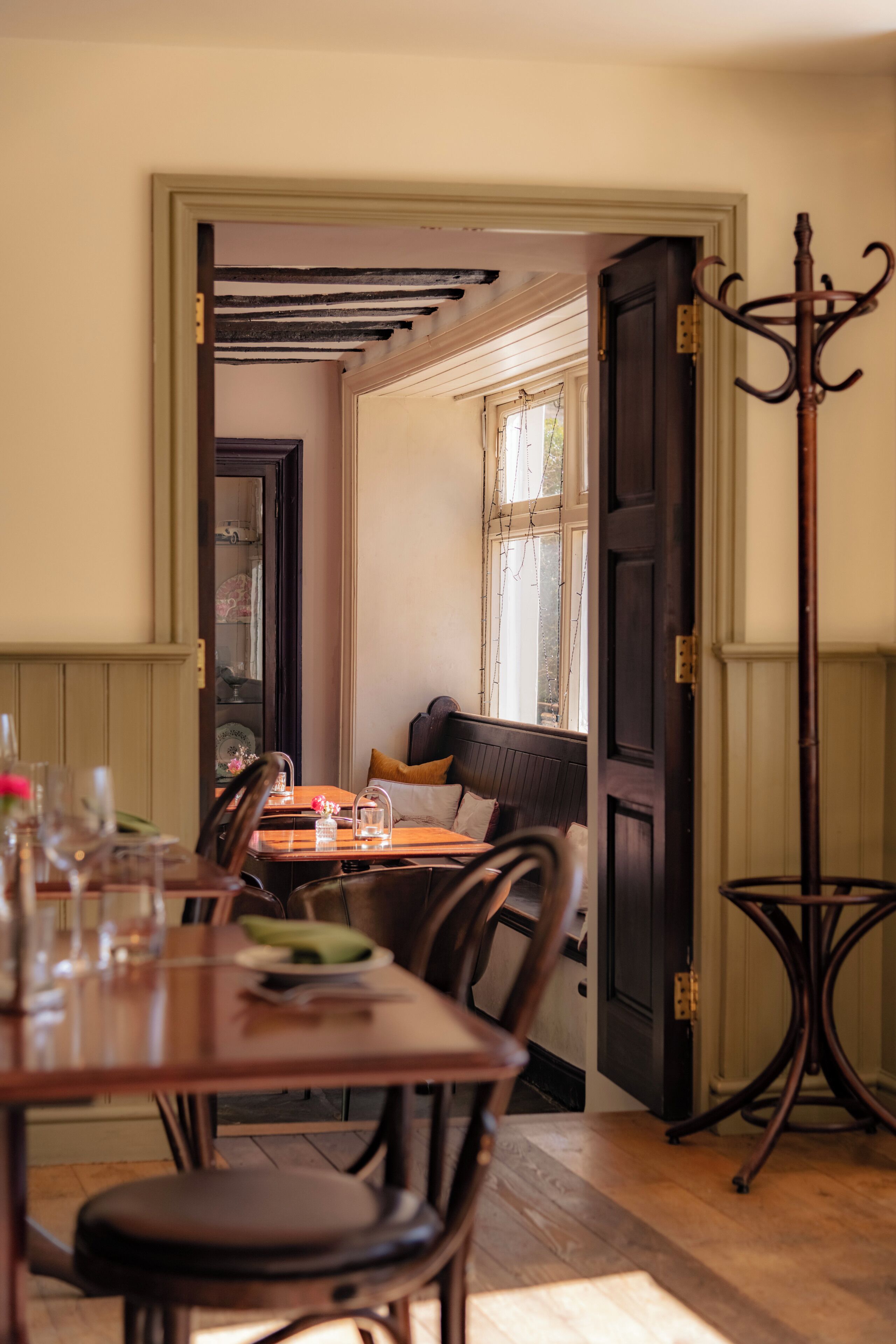 A dining area with a wooden table and chairs, a bench, and a coat rack.