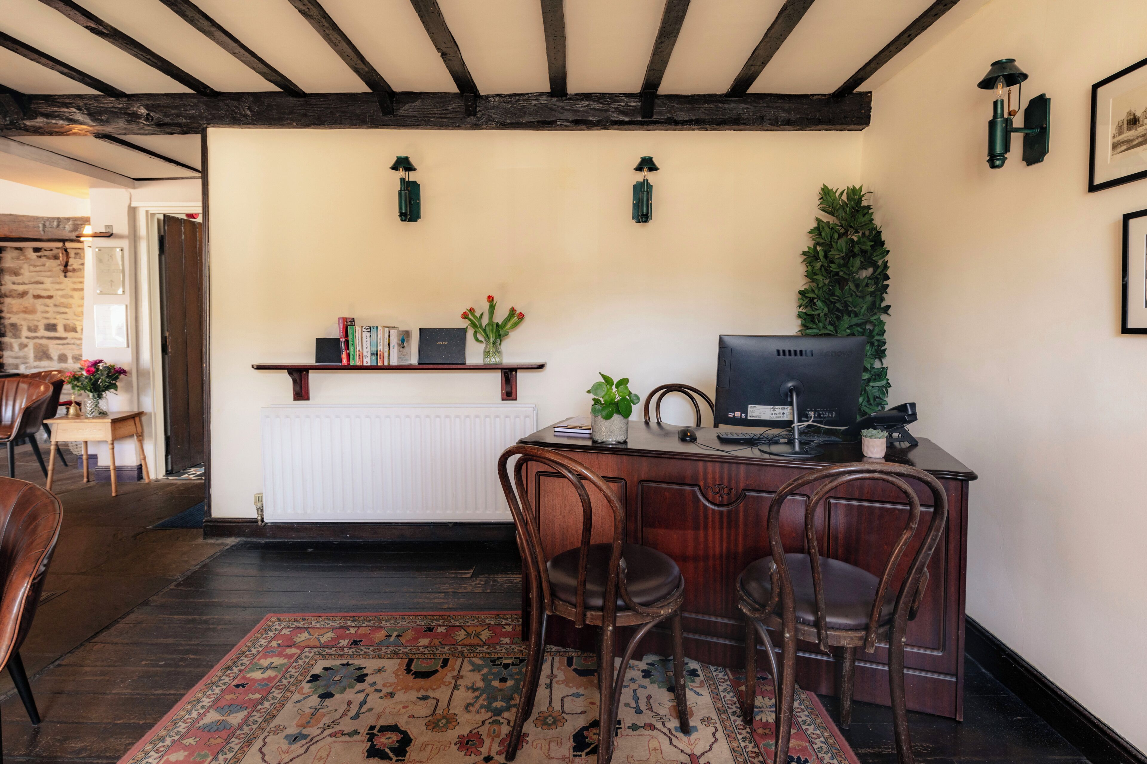 Una habitación con escritorio de madera, dos sillas, un radiador y una televisión.