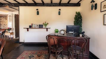 Una habitación con escritorio de madera, dos sillas, un radiador y una televisión.