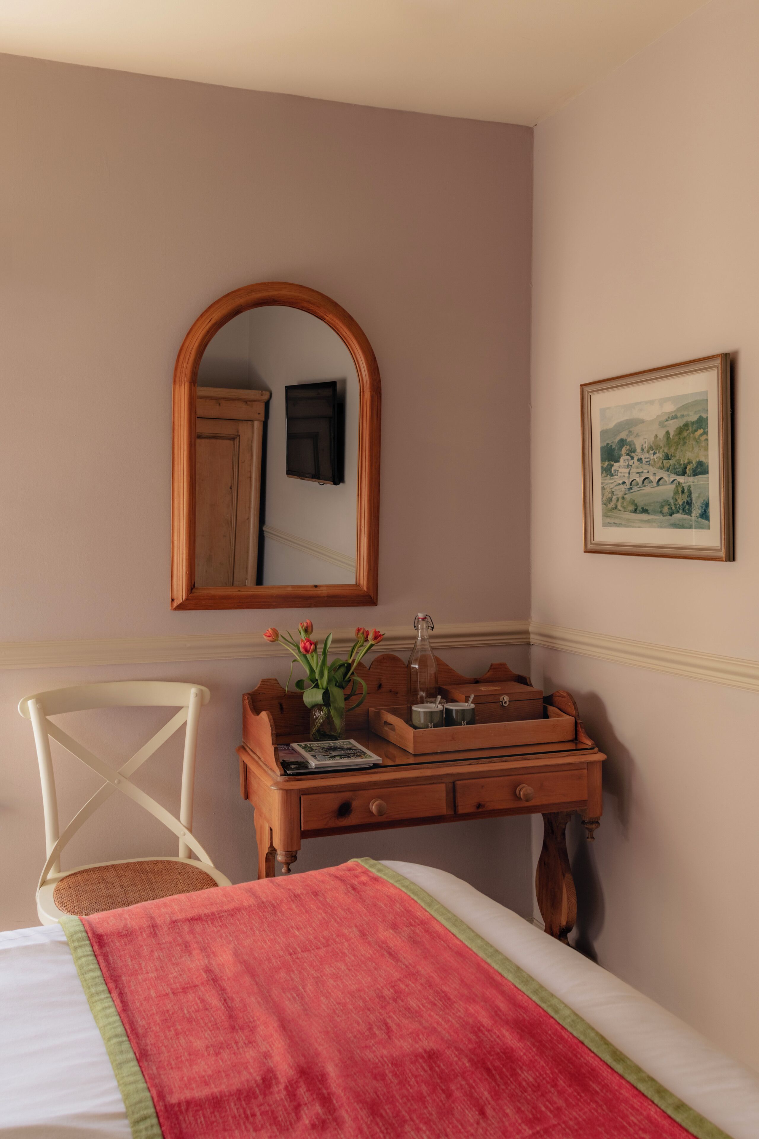 Un dormitorio con una cama, un aparador de madera, una silla, un espejo y un cuadro en la pared.