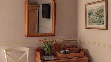 Un dormitorio con una cama, un aparador de madera, una silla, un espejo y un cuadro en la pared.