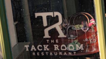 A restaurant window with the sign 'TACK THE ROOM RESTAURANT' and a table with wine glasses and a vase.