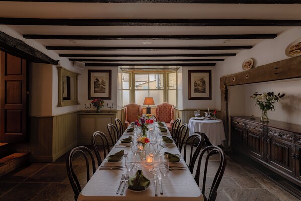 A dining room with a long table set for a meal, a window with a view, and a traditional architectural style.