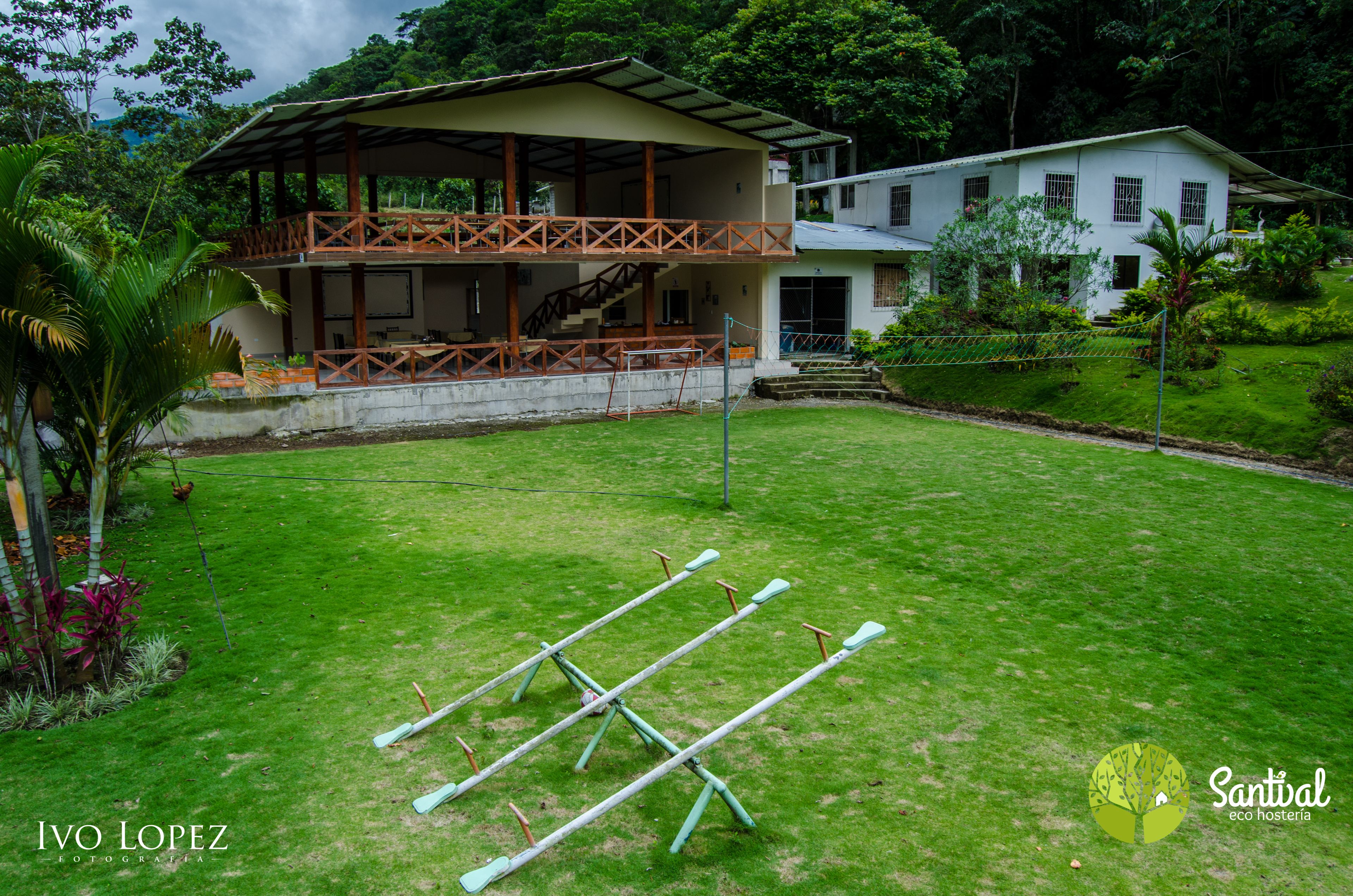 A two-story house with a balcony, a grassy yard, and exercise equipment.