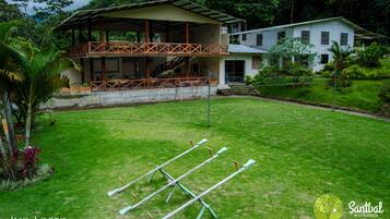 A two-story house with a balcony, a grassy yard, and exercise equipment.