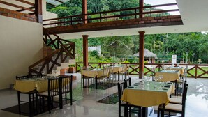 A restaurant with outdoor seating, a staircase, and a view of lush greenery. - Santval (Cumanda)