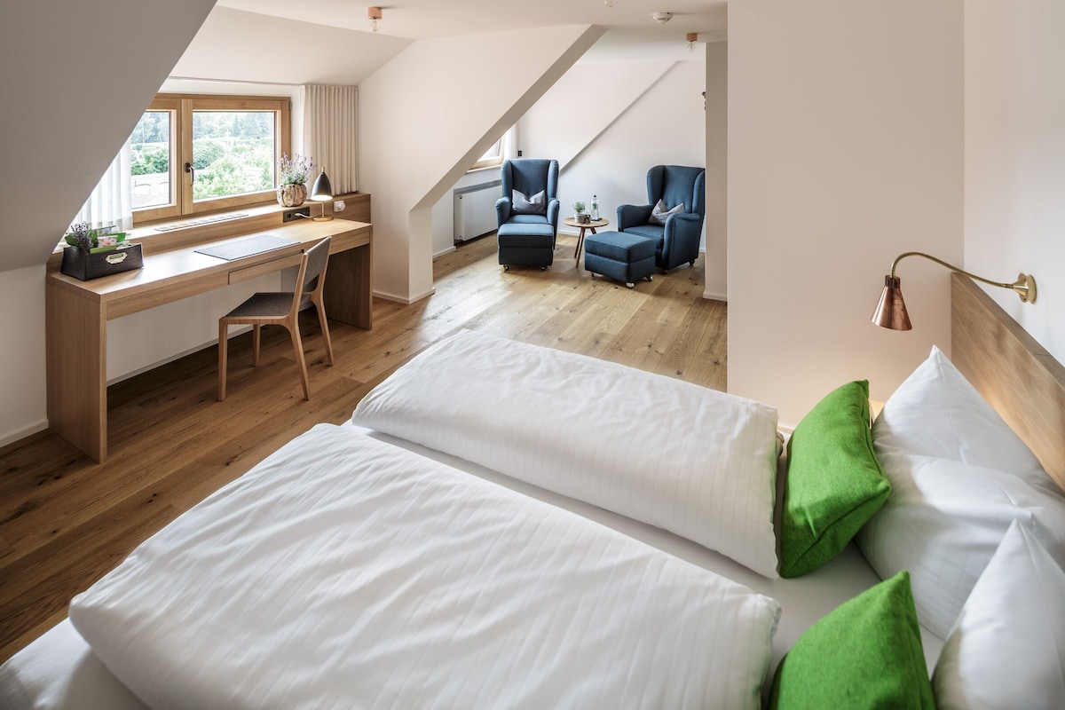 Een slaapkamer met een groot bed, een bureau en twee stoelen.